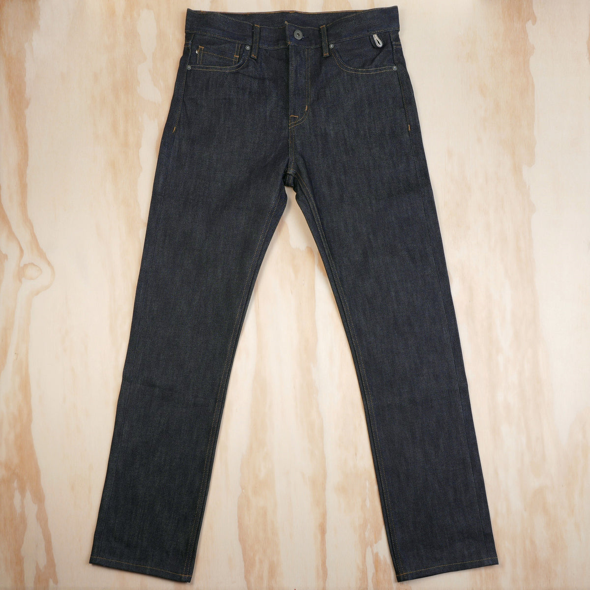 Dark indigo straight-fit selvedge jeans laid flat, front view.