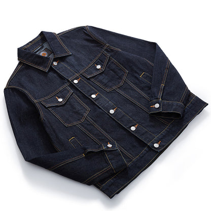 A dark indigo selvedge denim jacket with contrasting  orange stitching and silver metal snap buttons, laid flat on a white background.