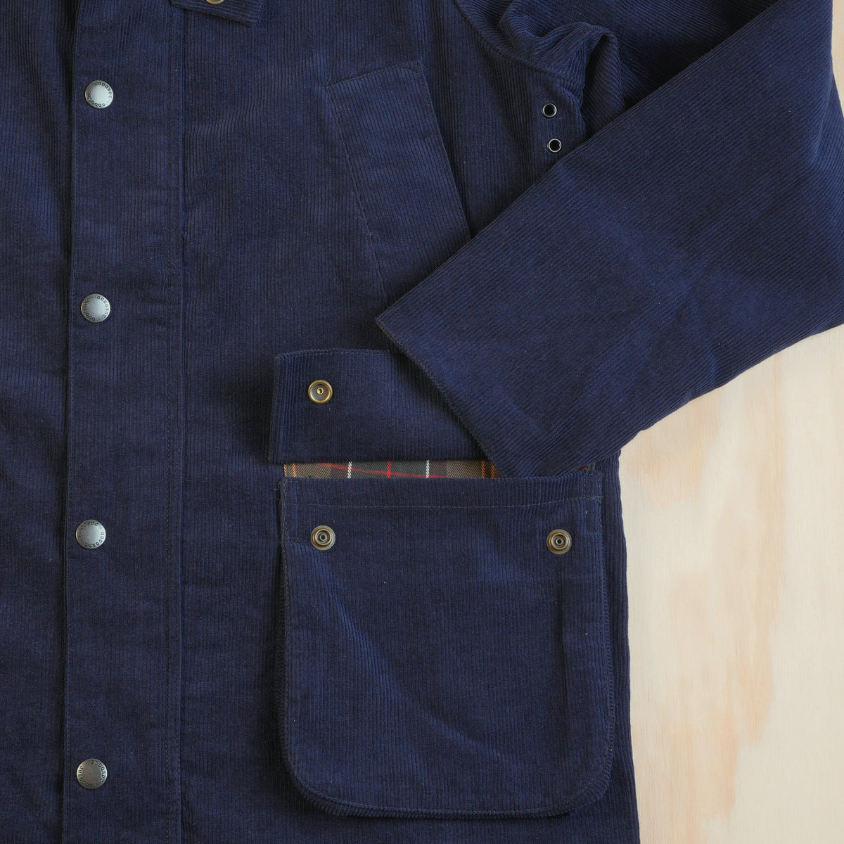 Close-up of the navy corduroy jacket sleeve, cuff and lower flap pocket with checked lining.