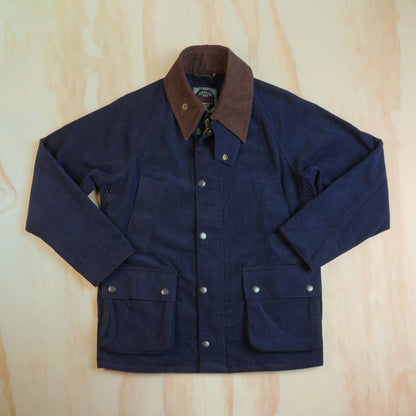 Front view of the navy corduroy hunting jacket with brown collar, snap storm flap and lower flap pockets, laid flat.