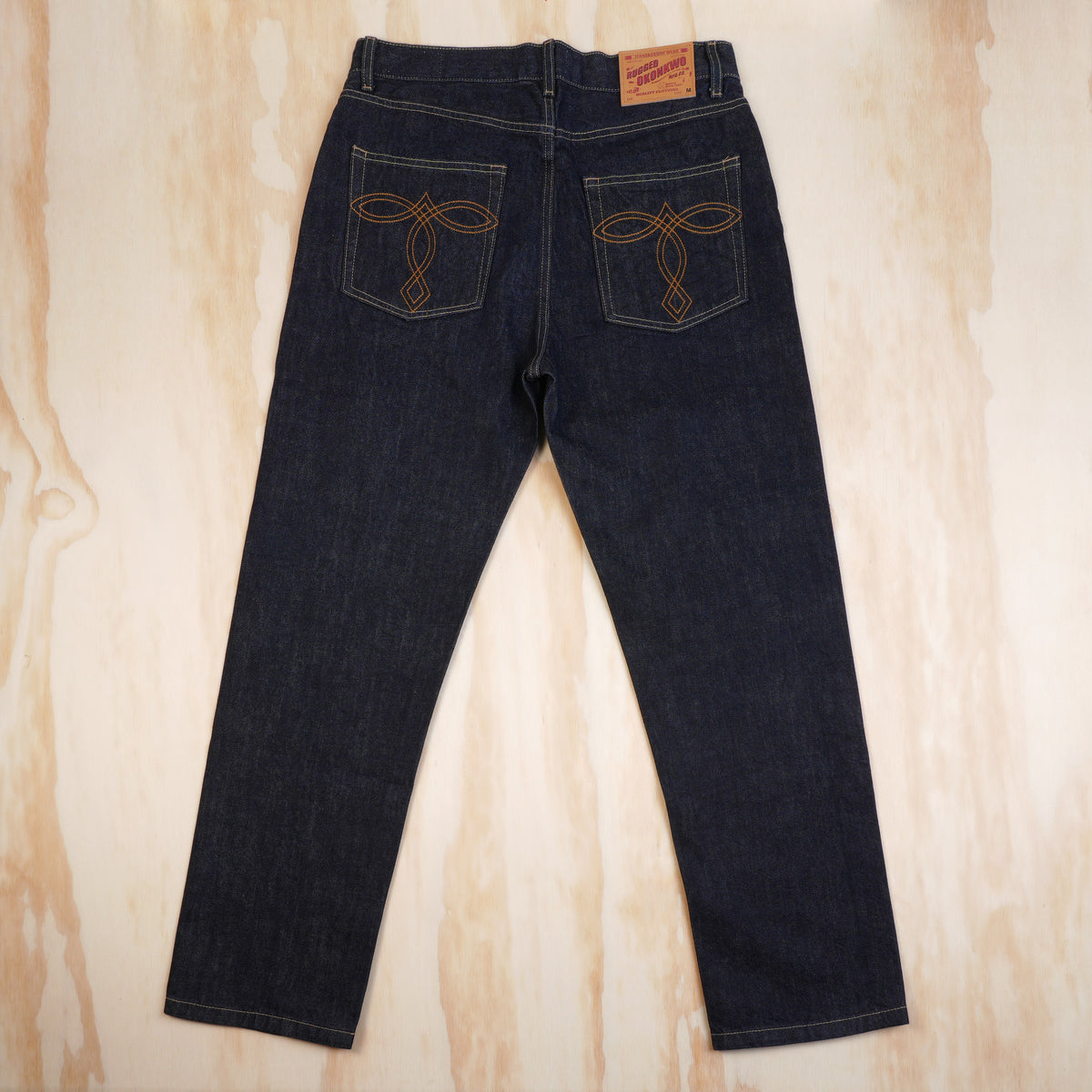 Back view of OKONKWO selvedge jeans showing embroidered pockets and leather patch