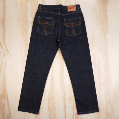 Back view of OKONKWO selvedge jeans showing embroidered pockets and leather patch