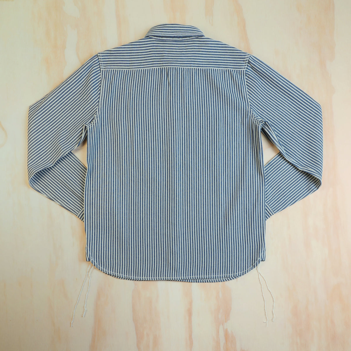 Back of the hickory stripe cotton work shirt, showing the horizontal striped yoke and curved hem.