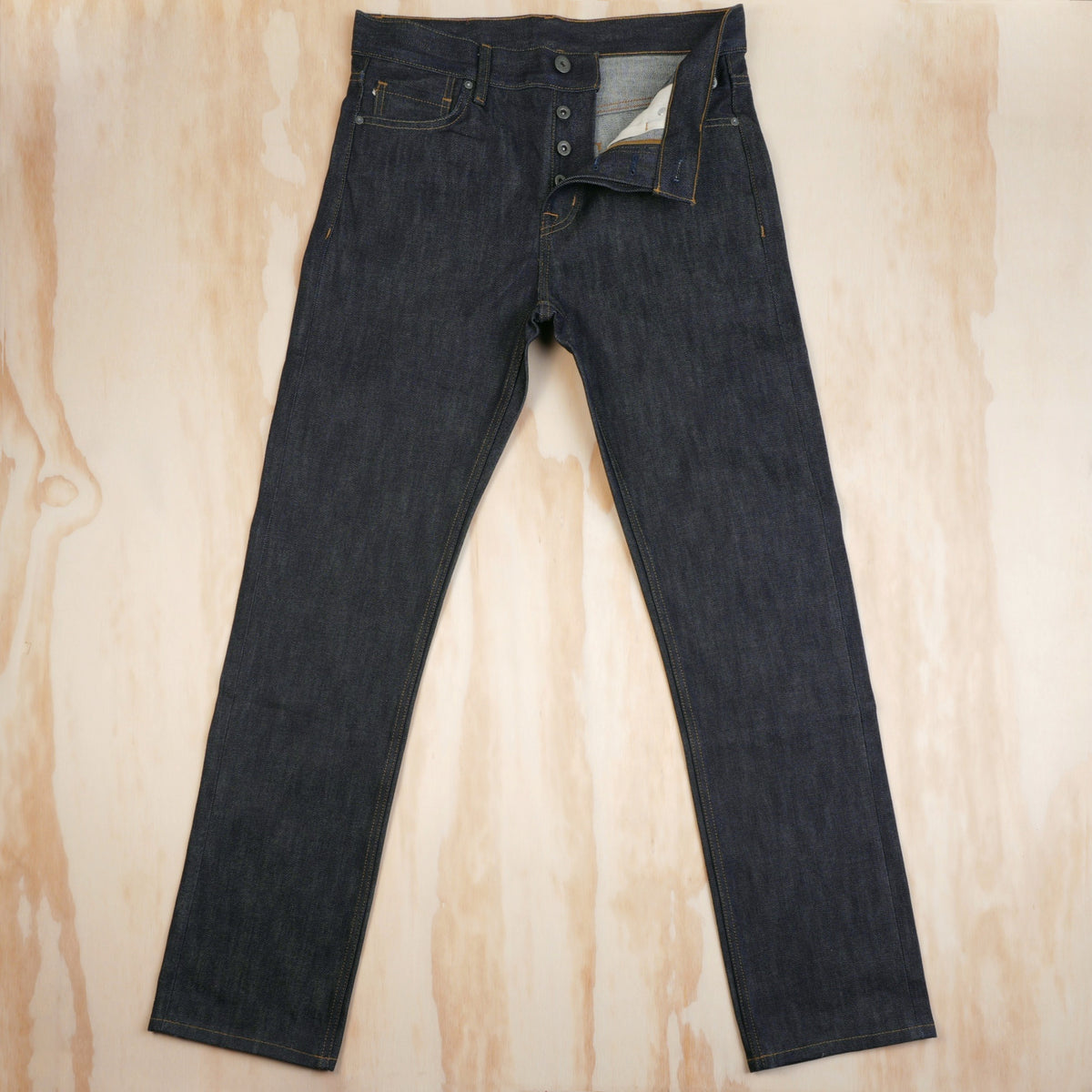 Front view of dark indigo selvedge jeans with the garment tag attached.
