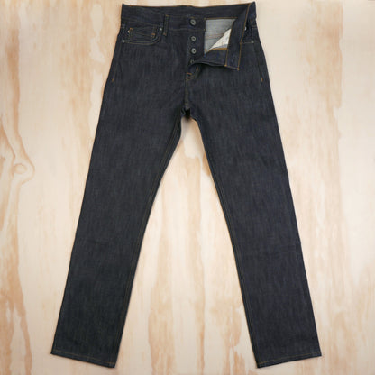 Front view of dark indigo selvedge jeans with the garment tag attached.